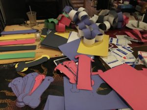 table with crafts supplies, paper chains, and paper dildos